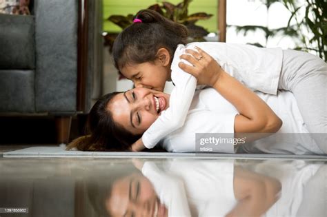Fille Embrassant Sa Mère Allongée Sur Un Tapis Dexercice Photo Getty