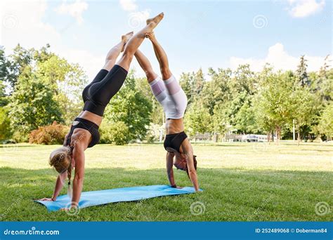 Two Young Sportswomen Doing Acrobatic Yoga Or Yoga Partner Together Outdoors In Fitness Park