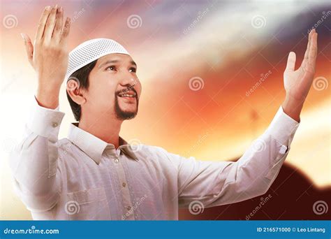Asian Muslim Man Standing While Raised Hands And Praying Stock Photo