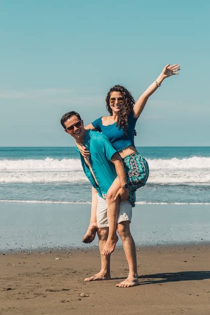 Feliz pareja amorosa divirtiéndose en la playa de arena de verano Foto Gratis