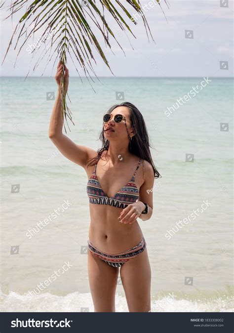 Asian Woman In Bikini Posture With Coconut Palm Leaf On Tropical Beach