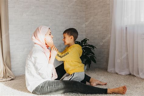 Premium Photo A Muslim Mother Happily Hugs And Plays With Her Son On The Floor At Home Woman