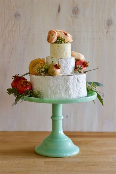 A Three Tiered Cake Sitting On Top Of A Green Plate Covered In Fruit And Flowers