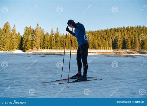 Handsome Male Athlete With Cross Country Skis Preparing Equipment For Training In A Snowy Forest