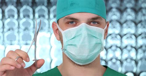 Close Up Of Medical Doctor Man Wear Surgical Mask Show Scissors In