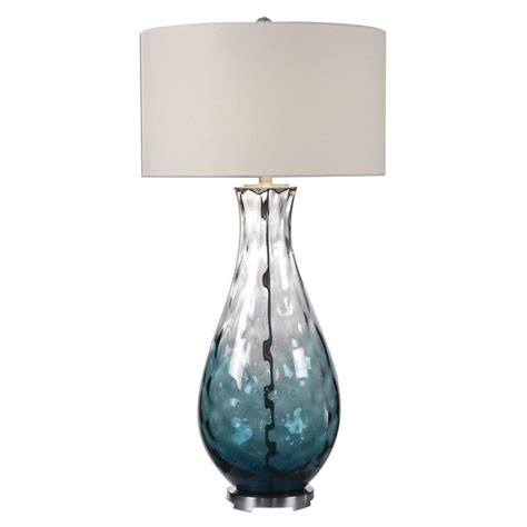 A Blue Glass Table Lamp With A White Shade
