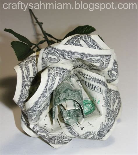 A Dollar Bill Origami Rose With Green Leaves On Its Stem Sitting On A