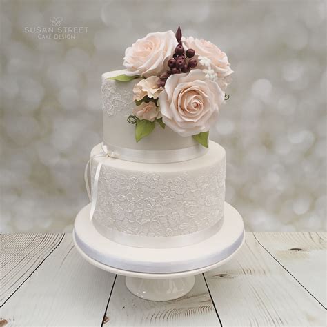 ivory and lace two tier wedding cake with pale peach roses sweet peas and berries tiered