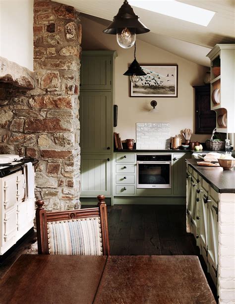 An Old Fashioned Kitchen With Stone Walls And Green Cabinets