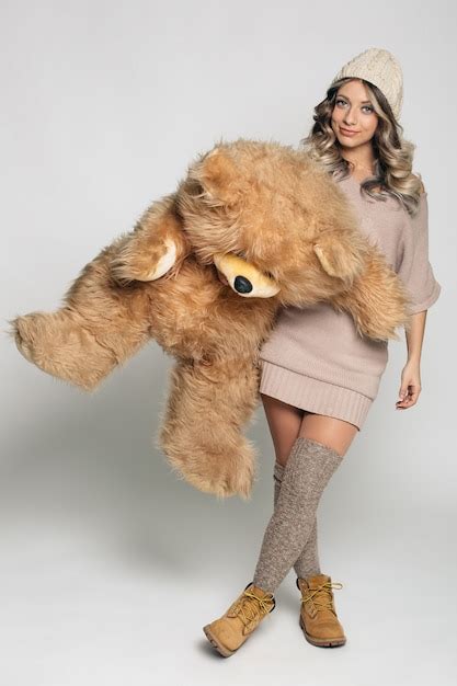 Free Photo Casual Smiling Young Woman In Knitted Clothes Holding Big Soft Teddy Bear