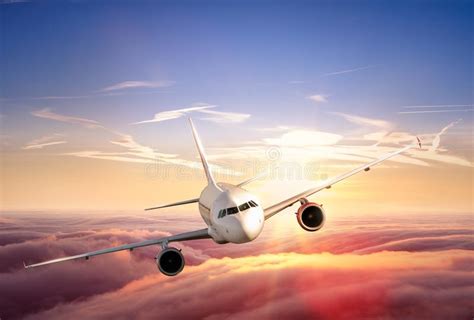 Airplane Jetliner Flying Above Clouds In Beautiful Sunset Stock Photo