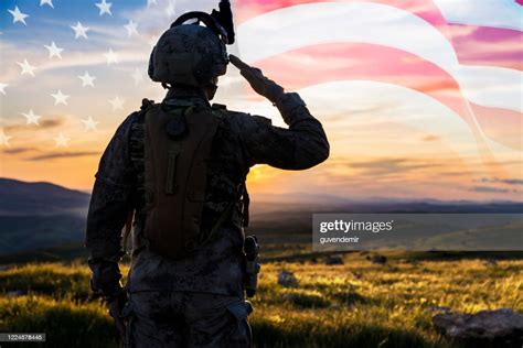 Silhouette Of A Solider Saluting Against Us Flag At Sunrise High Res