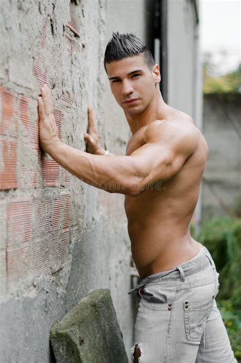 Muscular Young Latino Man Shirtless In Jeans Leaning Against Wall Stock