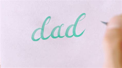 Hand Writing The Word Dad In Cursive On White Paper Dad In Cursive
