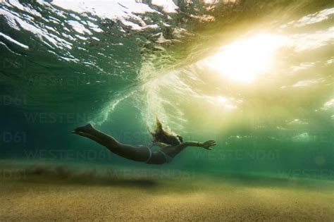 Side View Of Woman In Bikini Swimming Underwater Lizenzfreies Stockfoto