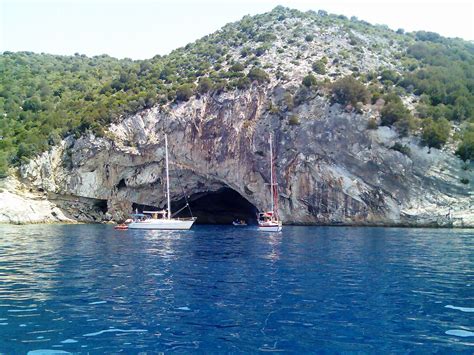 Two Boats Are In The Water Near A Cave