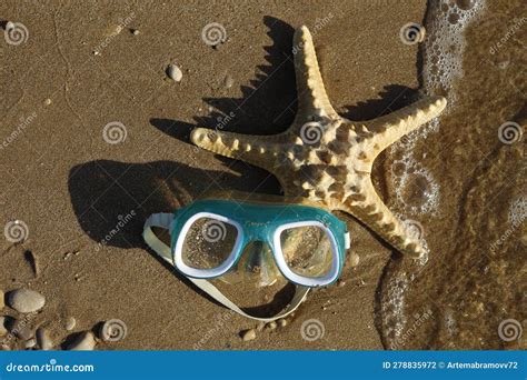 Top View Of Foaming Waves Hitting A Swimming Mask And A Starfish Lying