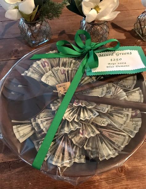 A Glass Platter With Money In It On Top Of A Wooden Table Next To Flowers