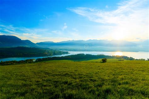 Beautiful Landscape Green Meadow And Lake With Mountain In Background