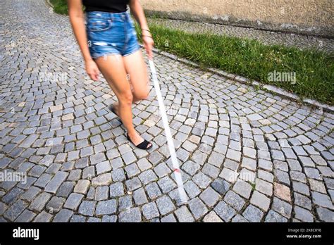 Blind Woman Walking On City Streets Using Her White Cane To Navigate