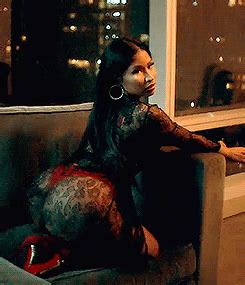 A Woman Sitting On A Couch In Front Of A Window With City Lights Behind Her