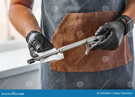 Close Up Of A Man In Apron Wiping His Firearm With A Cloth Stock Photo