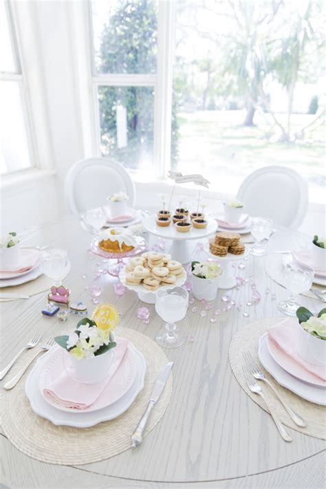 A White Table Topped With Plates And Cups Filled With Desserts Next To
