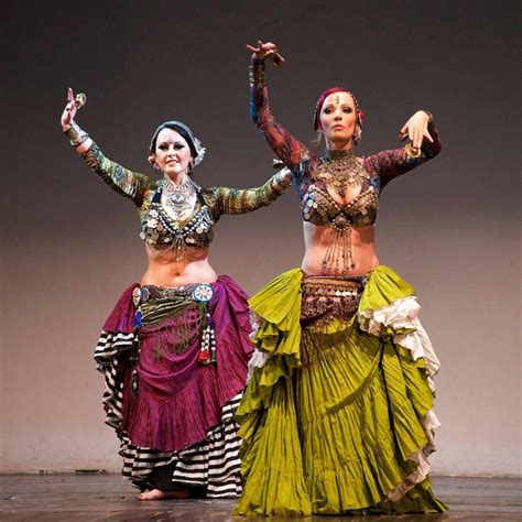 Two Women In Colorful Costumes Are Dancing On Stage