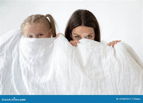 Mother And Daughter Hiding Behind White Blanket Indoors Stock Image