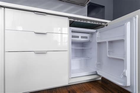 Uma pequena geladeira embutida no armário com gavetas na cozinha Foto