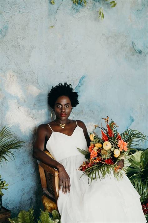 A Woman In A White Dress Sitting On A Chair Holding A Bouquet Of