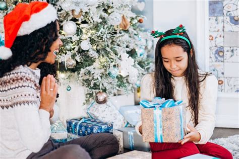 Mom And Daughter Sit On Carpet Opening Christmas Presents Stock Photo