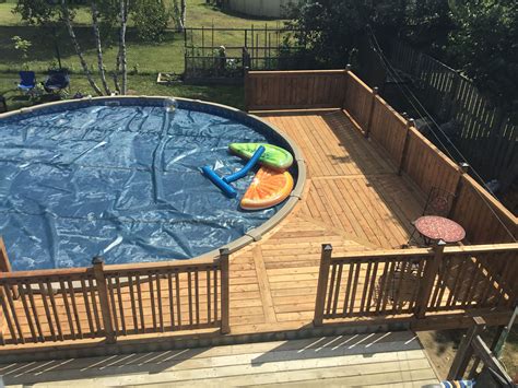 An Above Ground Pool Surrounded By Wooden Decking And Fenced In Area