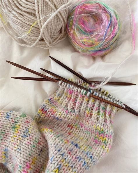Yarn And Knitting Needles On A Bed Next To Balls Of Yarn