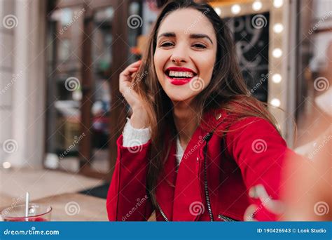 close up portrait of girl with gorgeous smile making selfie in red outfit outdoor photo of