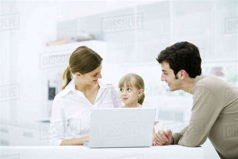 Family Gathered Around Laptop Computer Smiling Girl Looking At Mother Stock Photo Dissolve