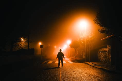 Man Standing In The Middle Of A Street At Night Under Thick Fog