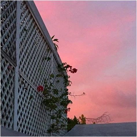 An Image Of The Sun Setting On Top Of A Building With Pink Clouds In