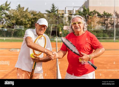 Portrait Of Two Senior Tennis Players Dressed In Sportswear Shaking