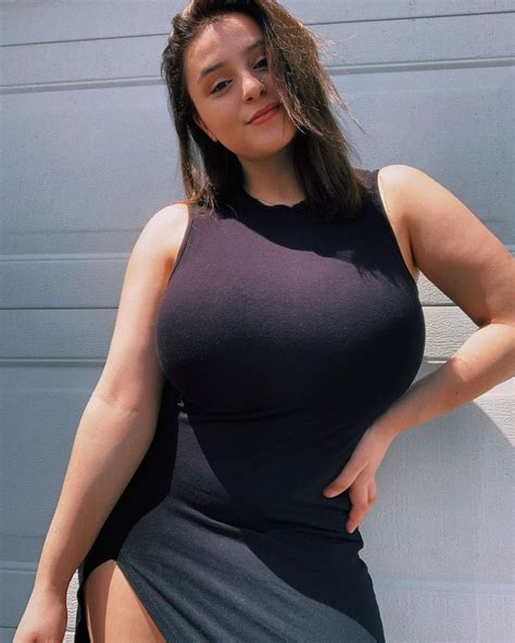 A Woman In A Black Dress Posing For The Camera With Her Hands On Her Hips