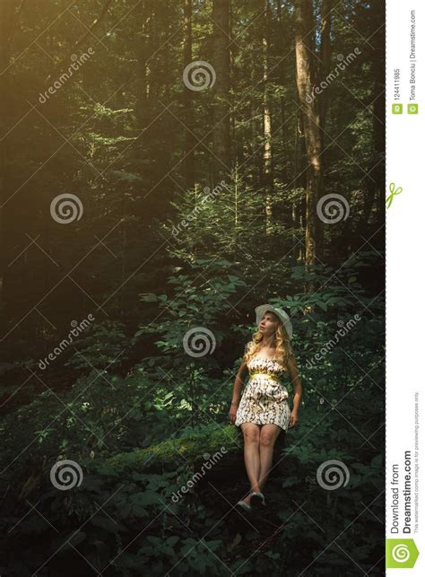 Woman With Blonde Hair Sitting On A Tree In The Forest