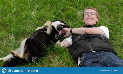 Young Happy Man Plays With Dog Lapland Reindeer Dog In Summer On Grass