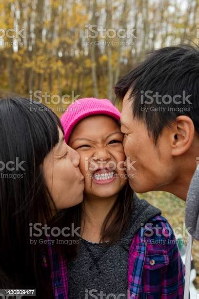 Padre Y Madre Besando Mejillas De Una Hija Feliz Y Linda Foto De Stock