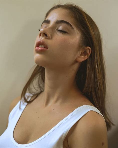 A Woman With Her Eyes Closed Wearing A White Tank Top And Looking Up