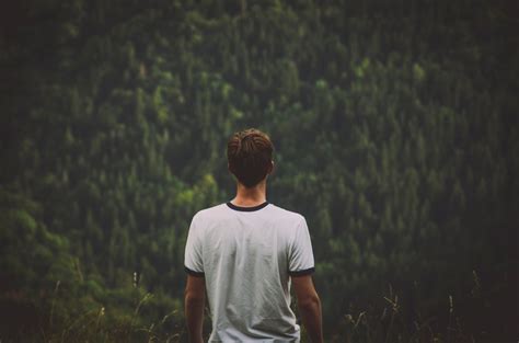 A Young Man Standing Back To Camera And Looking Off Into The Forest
