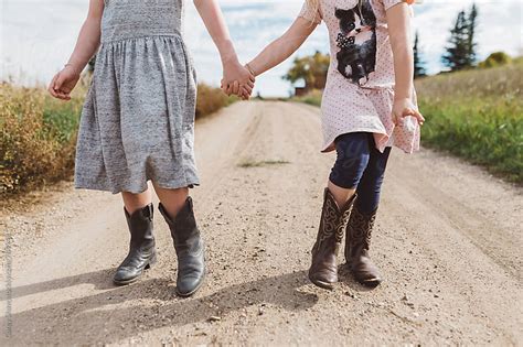 Young Sisters Wearing Cowboy Boots And Holding Hands By Carey Shaw