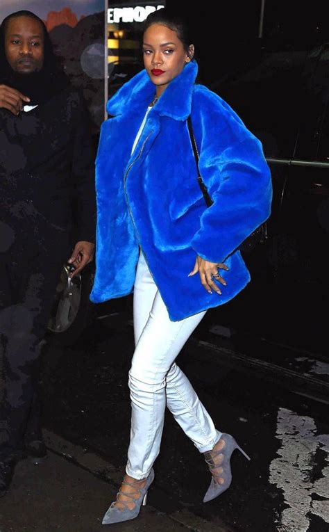 A Woman Walking Down The Street Wearing A Blue Coat