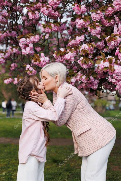 La Hija Besa A Su Feliz Madre Bajo Las Flores De Cerezo En Un Soleado