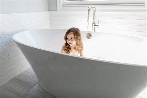 A Beautiful Young Girl Washing Herself In A Large Bathtub By Stocksy