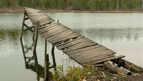 Old Broken Wooden Bridge Pier And Swan Birds Swim In Ripple Lake Water